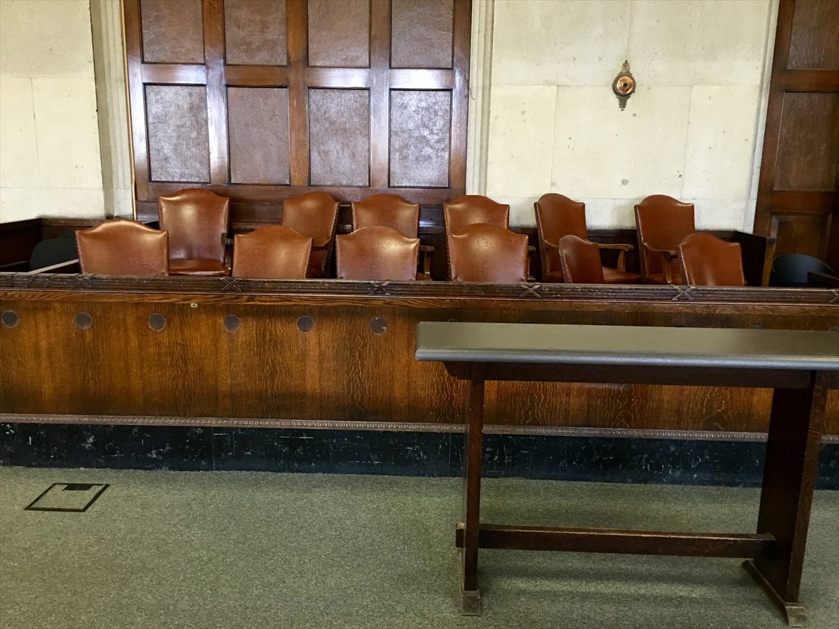 An empty jury box in a wood-paneled courtroom